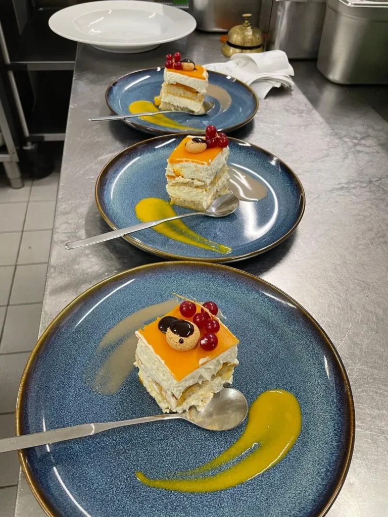 Mehrere Portionen Dessert-Creme-Schnitte auf Tellern im Service – The Dom Konstanz