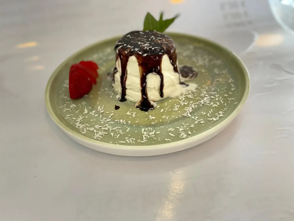 Cremiges Dessert mit Schokosauce und Erdbeere auf Teller – The Dom Konstanz