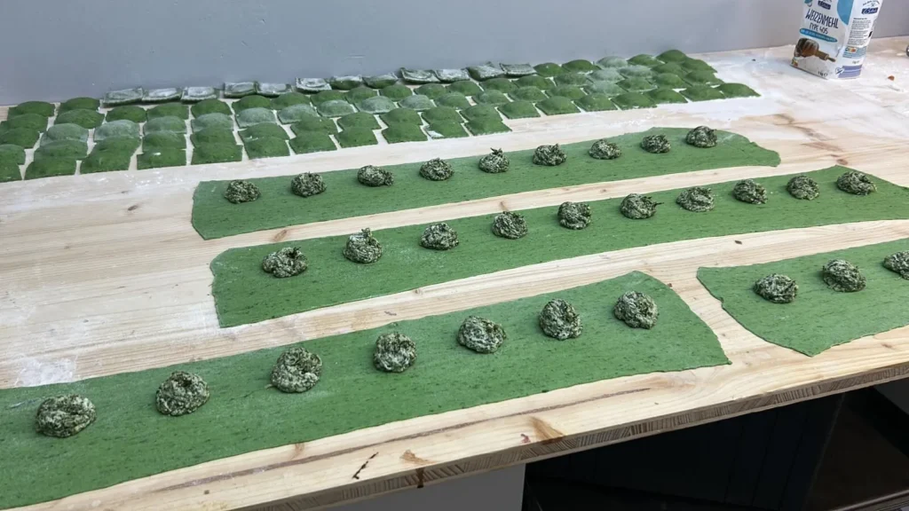 Füllung wird auf grünen Pasta-Teig gesetzt für Ravioli – The Dom Konstanz