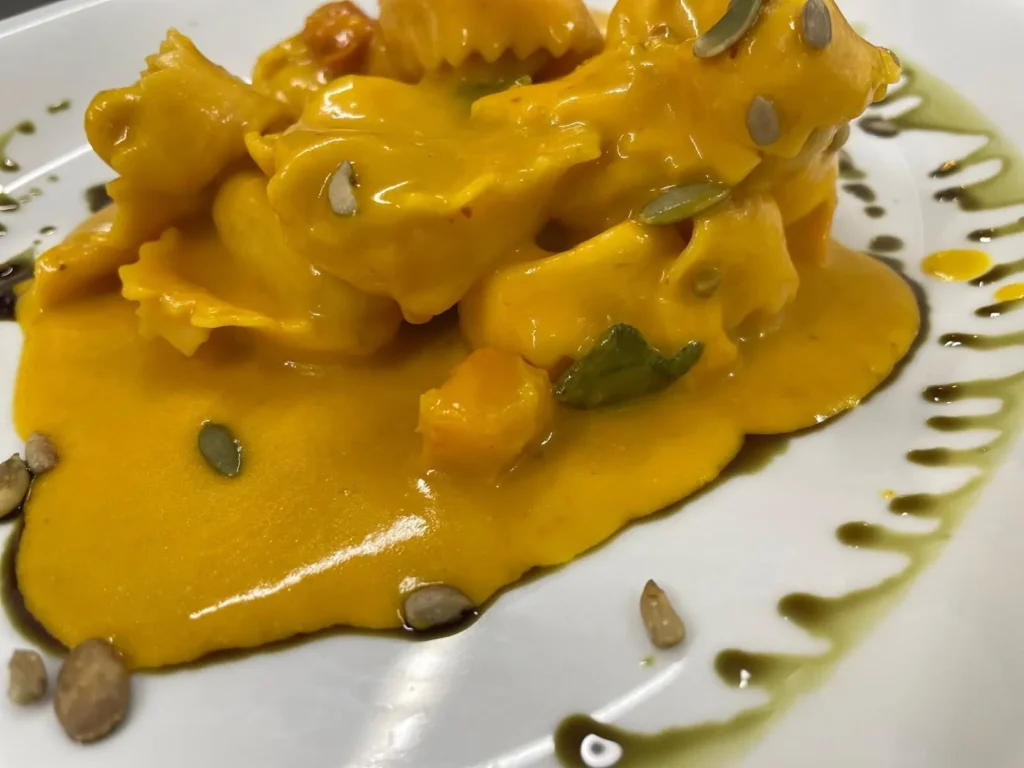 Detailaufnahme von Ravioli in Kürbiscreme mit Kernen und Pesto-Dekor – The Dom Konstanz