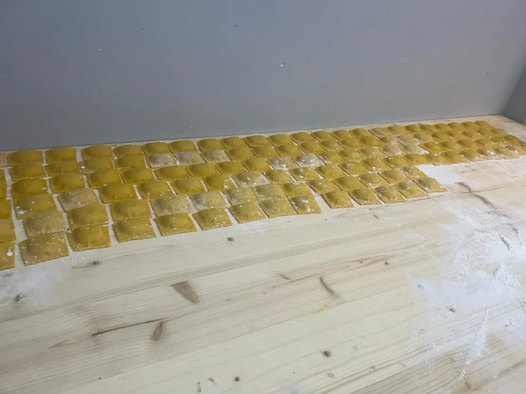 Viele handgemachte Ravioli auf bemehltem Holztisch in der Küche – The Dom Konstanz