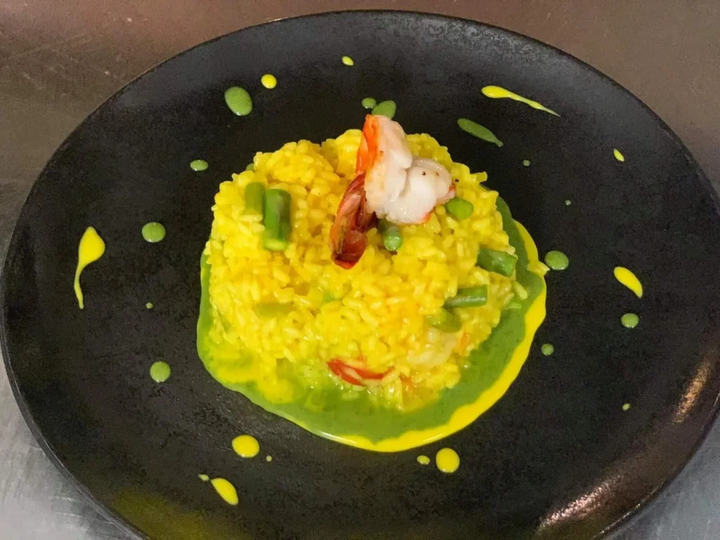 Risotto mit Garnelen in gelber und grüner Sauce auf schwarzem Teller – The Dom Konstanz