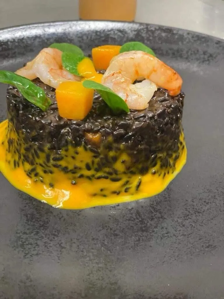 Schwarzes Risotto mit Garnelen und Mango auf Teller – The Dom Konstanz