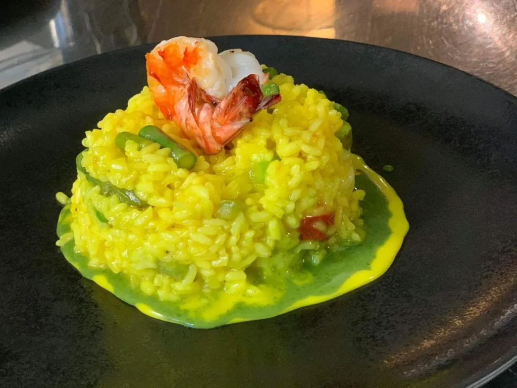 Spargel-Risotto mit Garnelen in grüner Sauce auf schwarzem Teller – The Dom Konstanz