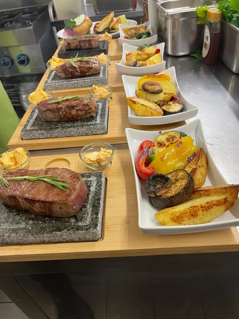 Mehrere Steaks auf heißem Stein mit Beilagen im The Dom Konstanz