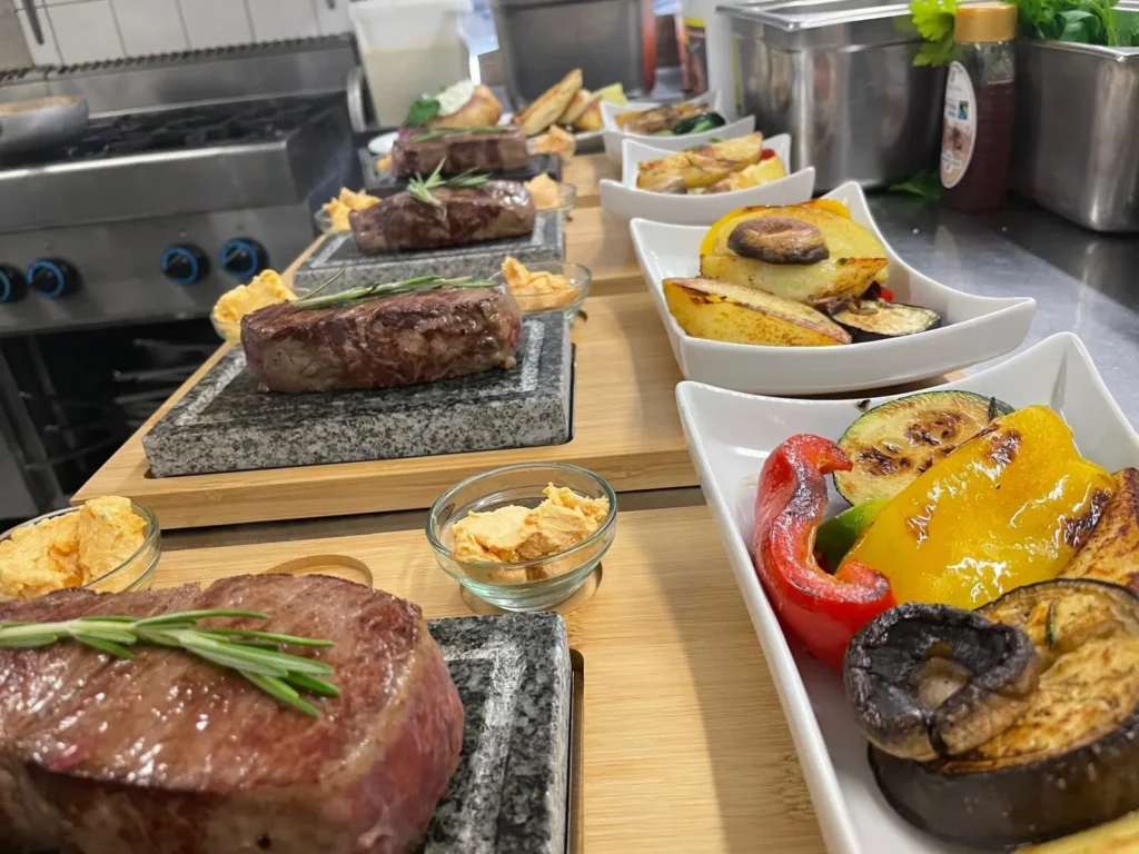 Mehrere Steaks auf heißem Stein mit Beilagen in der Küche – The Dom Konstanz