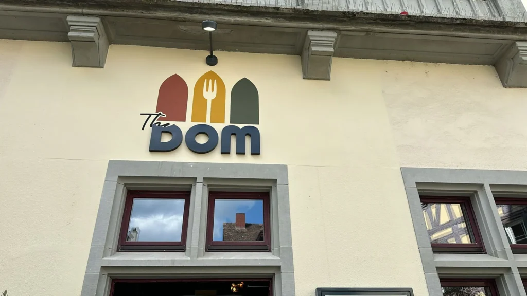 Das ikonische The Dom Logo mit Gotikbogen-Design an der Fassade des Restaurants in Konstanz