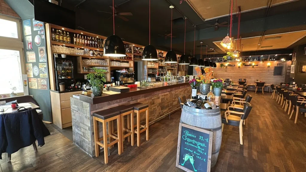 Panoramablick auf die Bar und den Gastraum im The Dom Konstanz mit Industrieleuchten und Weinfass