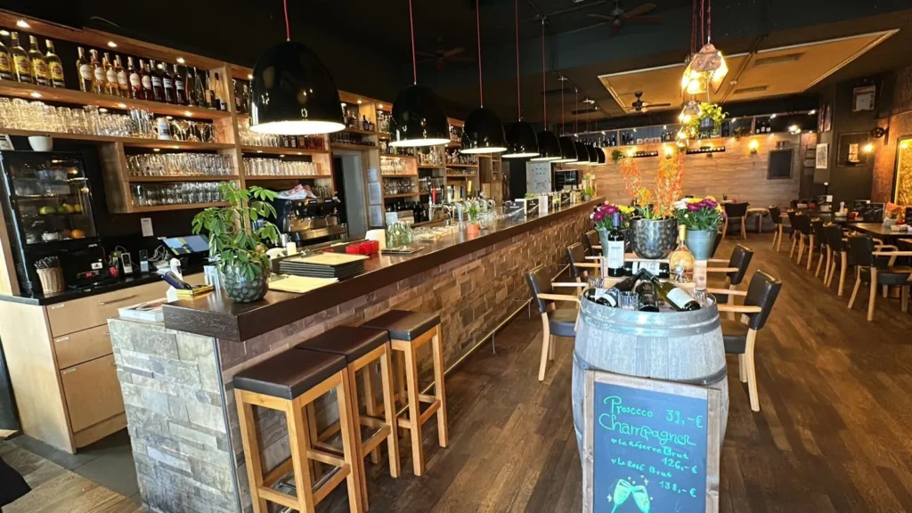 Stilvolle Bar im The Dom Konstanz mit Holzhockern, Weinfass und Prosecco-Kreidetafel