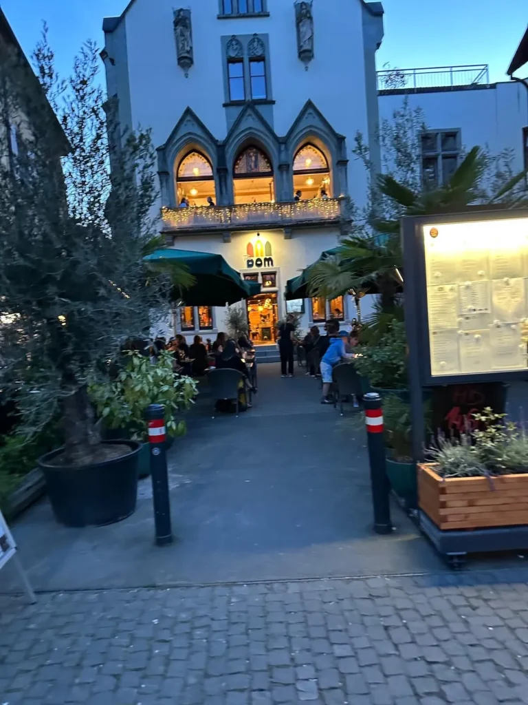 Eingangsbereich von The Dom Konstanz am Abend mit Dom-Logo, Lichterketten und Speisekarte