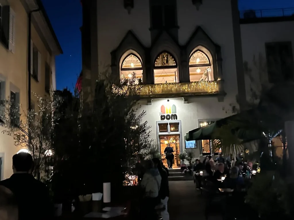 Naechtliche Ansicht von The Dom Konstanz mit Logo, Palmen und Olivenbaeumen vor der gotischen Fassade