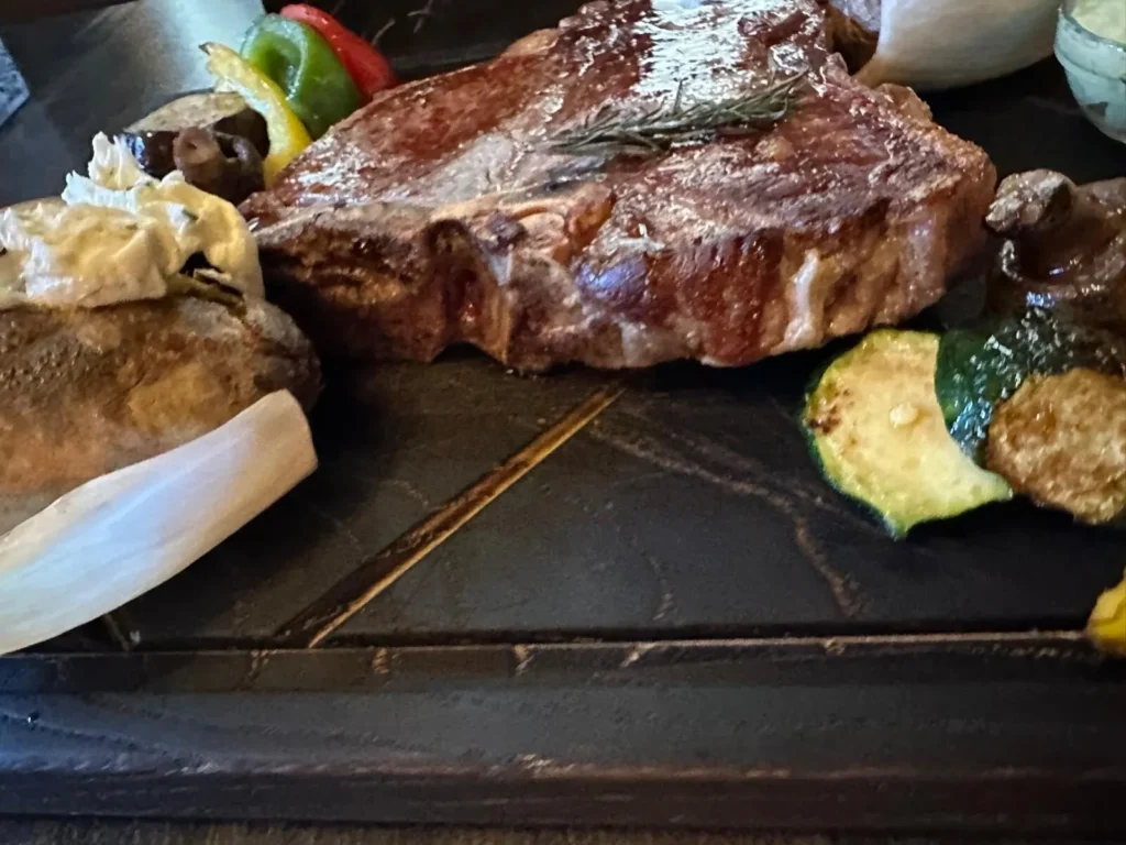 Fiorentina-Steak auf Holzbrett mit gegrillter Zucchini, Paprika und Brot im The Dom Konstanz