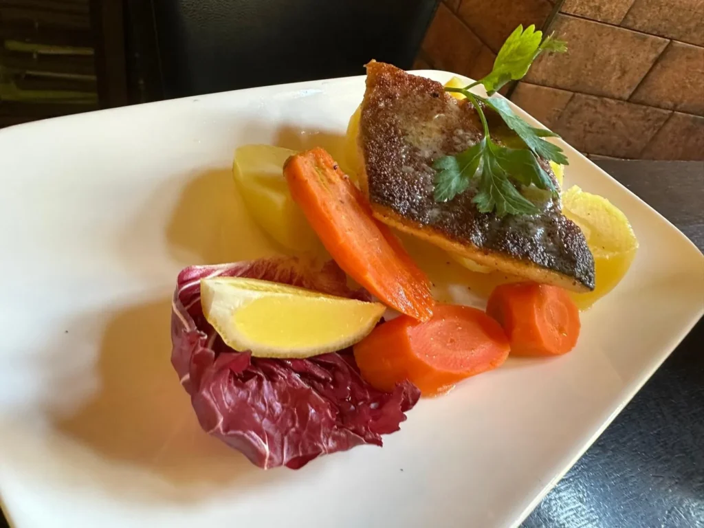 Gebratenes Fischfilet mit glasierten Karotten, Radicchio und Zitronenspalte im The Dom