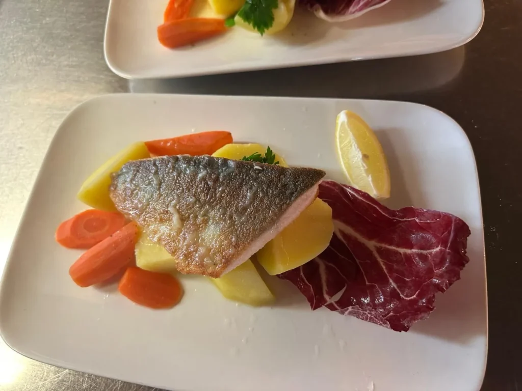 Fischfilet auf Kartoffeln mit Karotten, Radicchio und Zitronenspalte angerichtet bei The Dom Konstanz