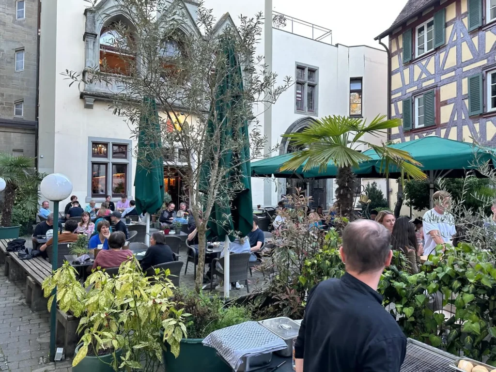 Gaeste auf der Terrasse von The Dom Konstanz zwischen Olivenbaeumen und mediterranen Pflanzen