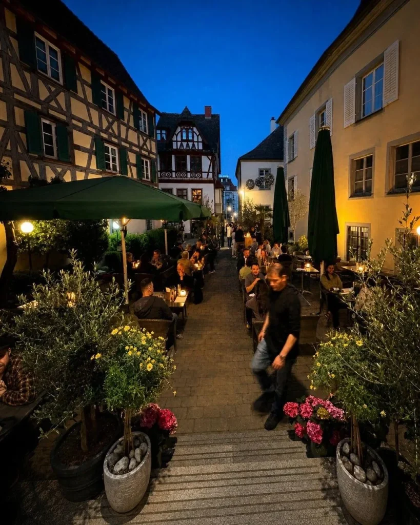 Stimmungsvolle Aussenterrasse von The Dom Konstanz bei Nacht mit Gaesten zwischen Fachwerkhaeusern