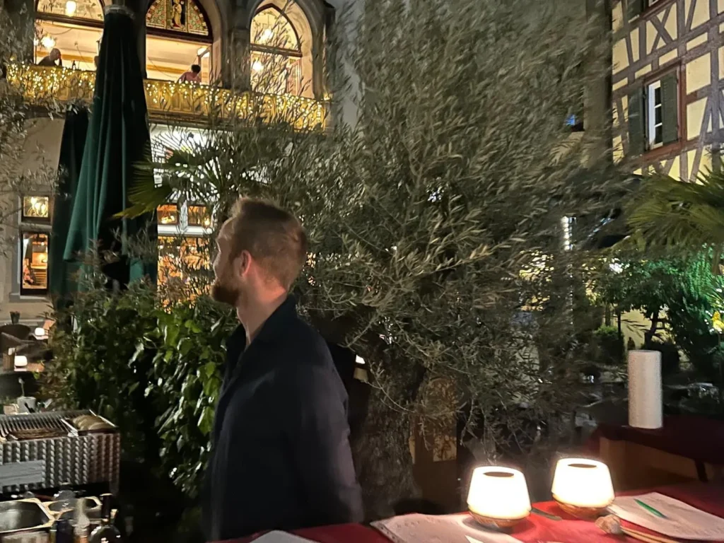 Mitarbeiter auf der Terrasse von The Dom Konstanz bei Nacht neben Olivenbaum mit stimmungsvollen Tischlampen